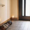 手すりと常夜灯があり、靴を壁際に整えて床を空けた玄関の様子