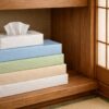 木製の棚に置かれた複数のティッシュペーパー。使いかけと未使用の箱が並び、切らさず安心して暮らせる日常の風景。
